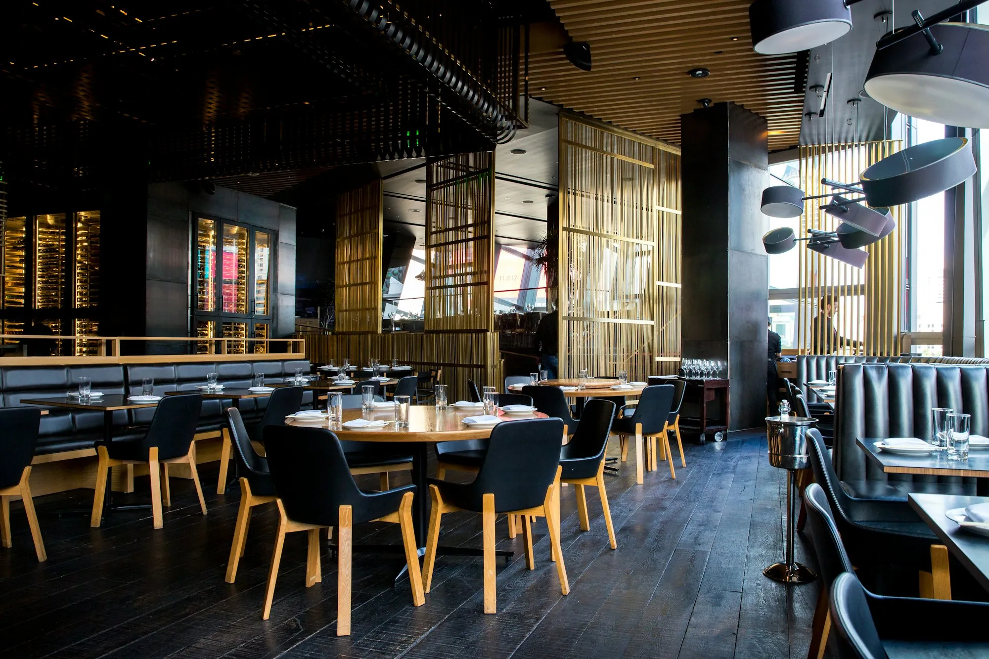 A dimly lit restaurant with dark wood tables and leather banquettes